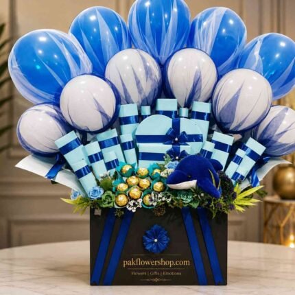 Luxury gift hamper Pakistan with blue balloons, chocolates, decorative gift boxes, plush dolphin, and floral accents.