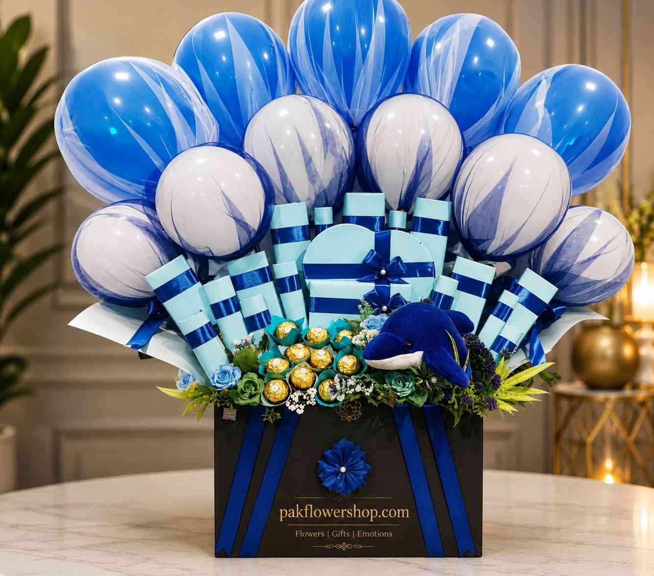 Blue Celebration Box Luxury gift hamper Pakistan with blue balloons, chocolates, decorative gift boxes, plush dolphin, and floral accents.