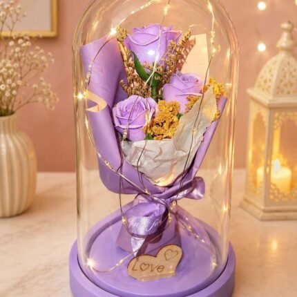Glass Dome Flowers Pakistan with lavender roses and warm LED lights.