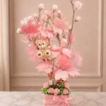 Flower tree Lahore with pink roses, teddy bear, and decorative leaves.