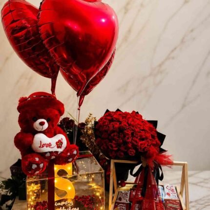 Elegant gift hamper Pakistan with red roses, heart balloons, chocolates, and teddy bear for special occasions.