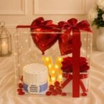 Clear acrylic box with a custom cake and balloons for flower delivery in Lahore