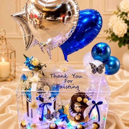 Clear gift box with blue heart balloons and a chocolate cake to send gifts to Pakistan online