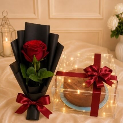 Single wrapped red rose next to a glowing cake box for flower delivery in Pakistan