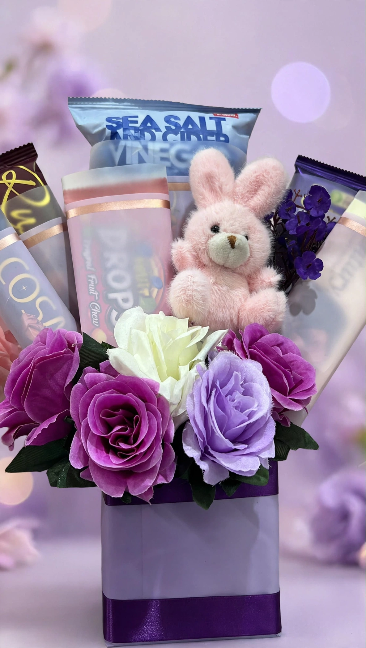 Close-up of roses, bunny plush and snacks in the lavender gift bag