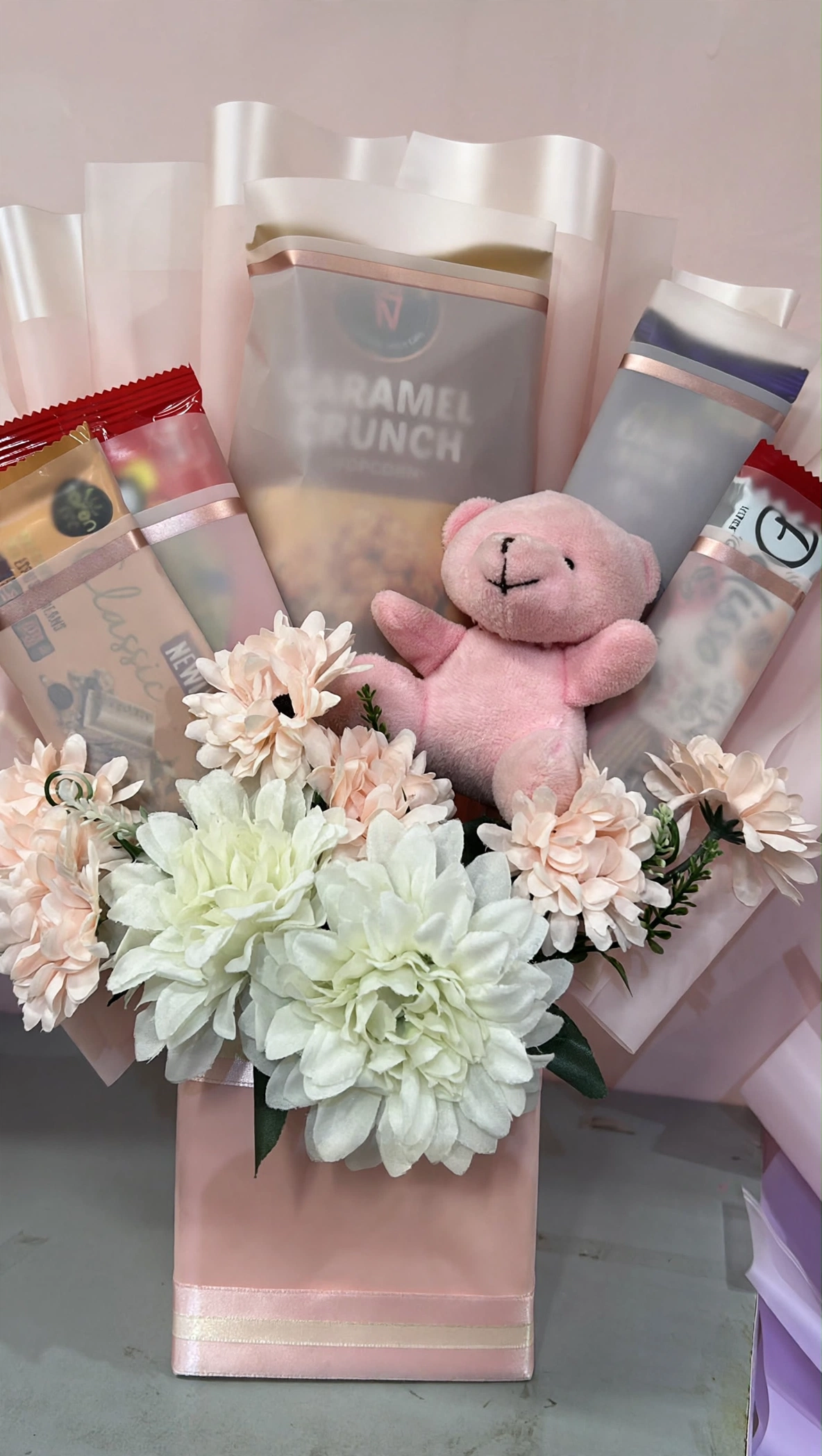 Close-up of chrysanthemums, teddy and snacks in the blush gift bag