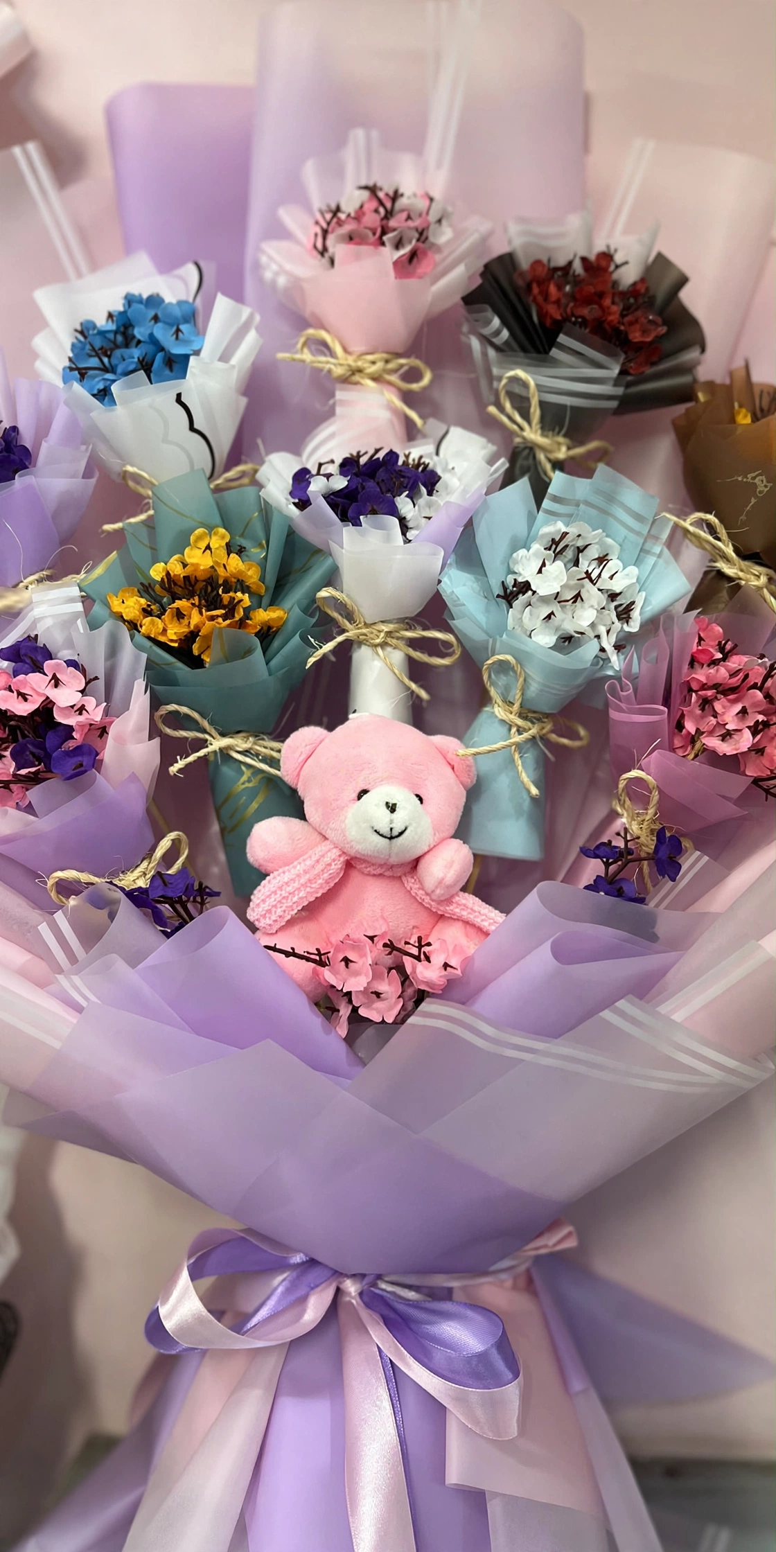 Close-up of palm-size handmade mini bouquets and pink teddy